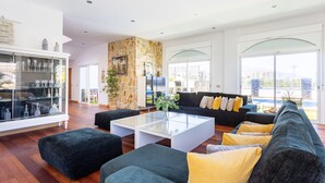 A spacious living room with a glass coffee table, dark sofas, and a stone accent wall. - Villa Syrah Tenerife (Puerto De La Cruz)