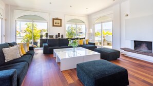 A spacious living room with a black sofa set, a white coffee table, and a fireplace. - Villa Syrah Tenerife (Puerto De La Cruz)