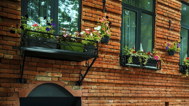 A brick building with multiple windows, some with flower boxes. There is a sign indicating a hotel and a tea room. - Tea for Two Hotel (Tbilisi)