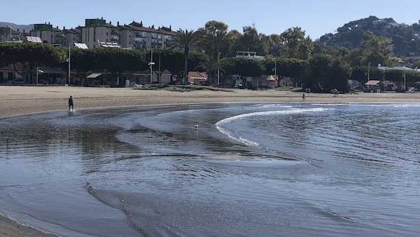 A beach with a clear sky, calm water, and buildings in the background. - APT.1ST LINE BEACH. AT STREET LEVEL. 2 BEDROOMS/4 PERSONS. WIFI AND NETFLIX.  (Málaga)