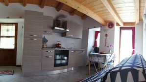 Een moderne keuken met houten balken, roestvrijstalen apparatuur en een eethoek met een tafel en stoelen.