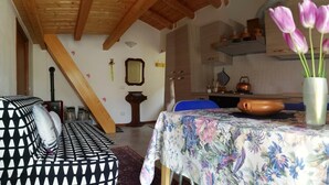 Een gezellige woonkamer met een gestreept sofa, een tafel met een bloemrijk tafelkleed, en een vaas vol tulpen.