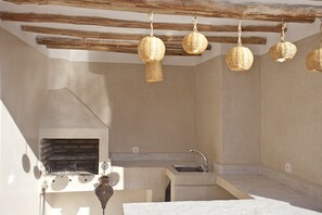 A kitchen with a built-in grill, a sink, and hanging wicker pendant lights. - Riad Al Riad (Marrakech)
