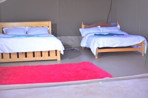 Dos camas de madera con ropa de cama blanca, una alfombra roja y una pared gris.