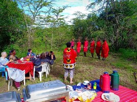 Un espacio de comedor al aire libre con mesas y sillas, rodeado de follaje.