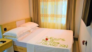 Una habitación de hotel con cama, mesita de noche y ventana con cortinas.