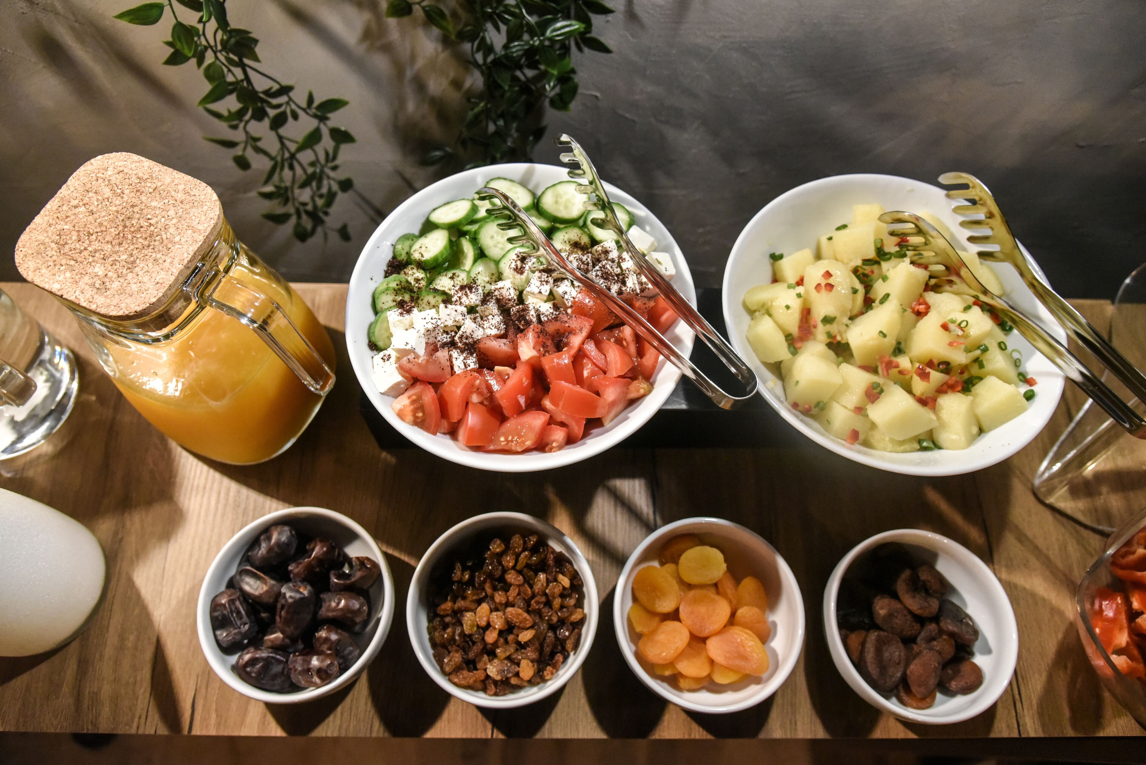 Une table sur laquelle on trouve divers aliments, notamment des bols de fruits, des noix et un verre de jus.
