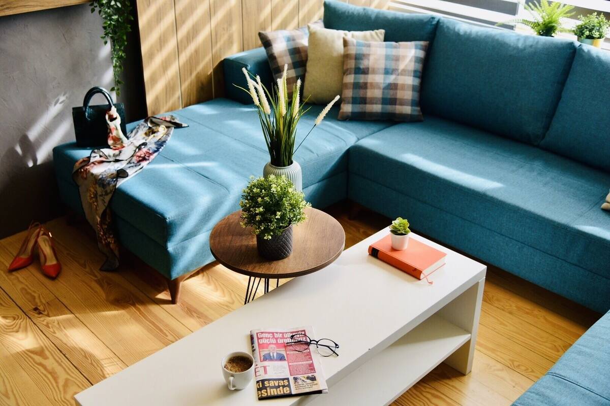 A modern living room with a blue sofa, a coffee table, and a small bookshelf.