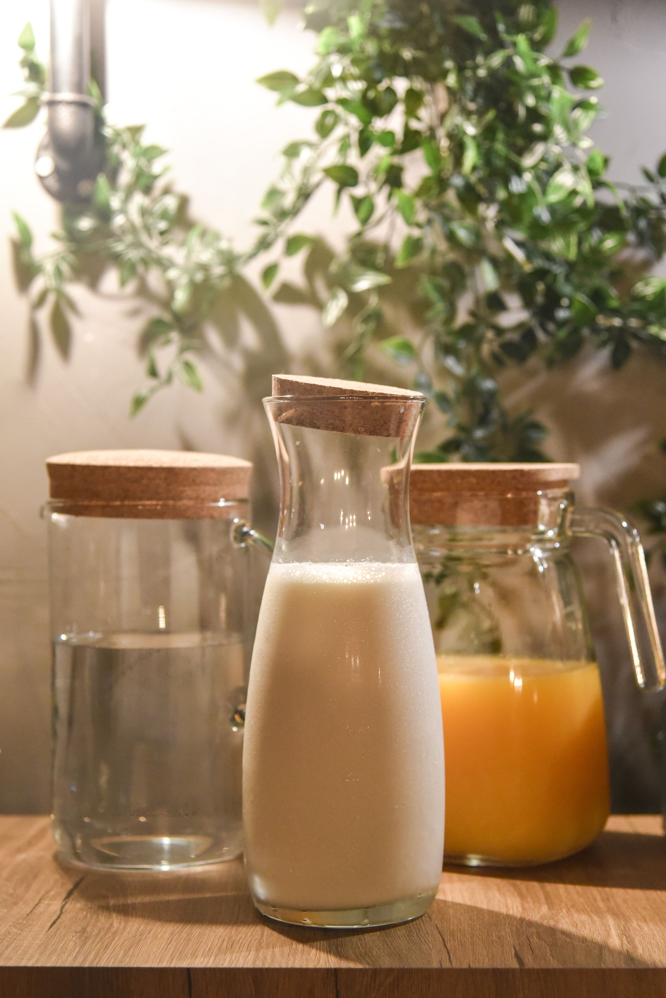 Three glass containers with cork stoppers on a wooden surface.