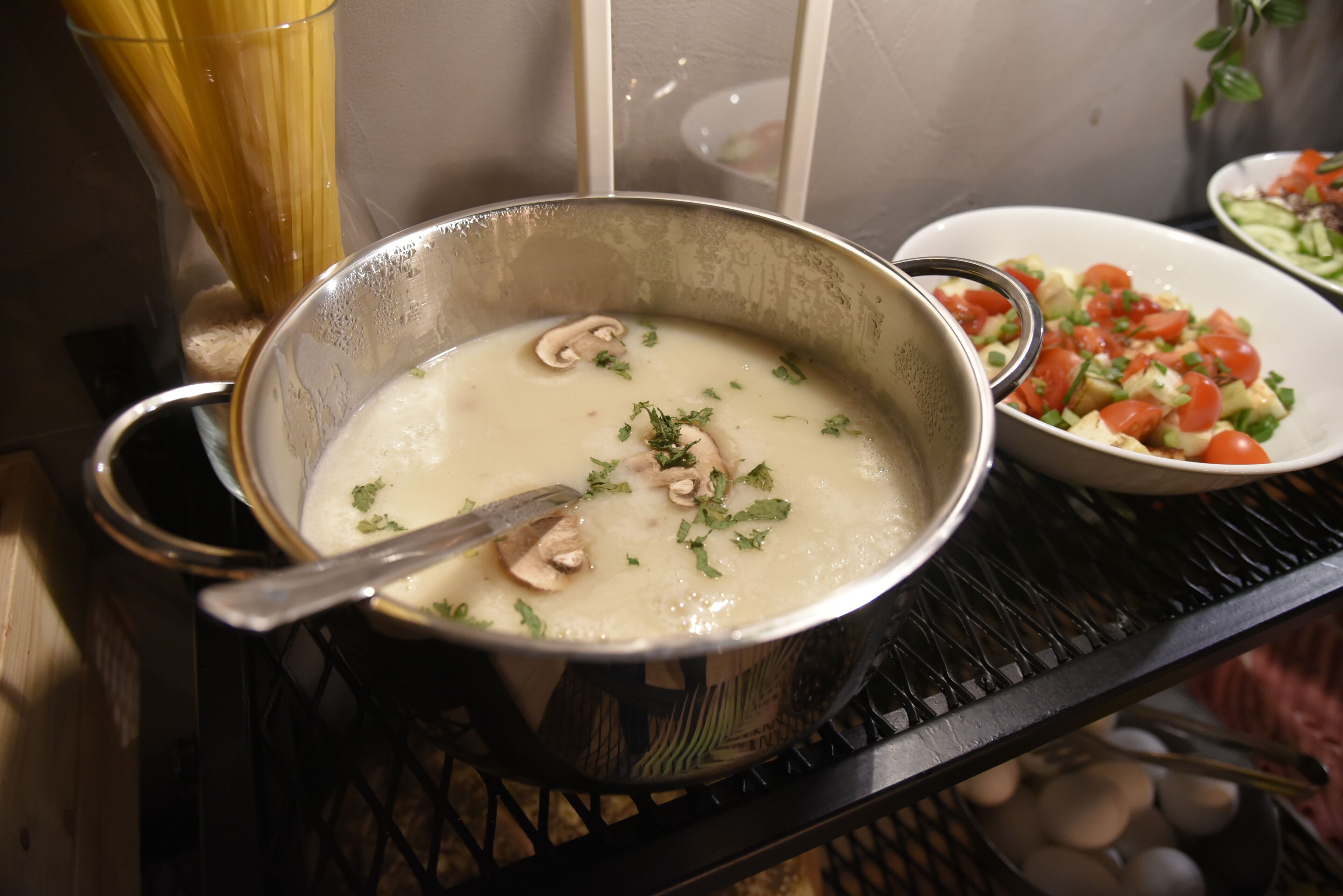 Una olla de sopa cremosa con champiñones y hierbas sobre una estufa.