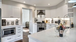 A modern kitchen with white cabinetry, a central island, and a built-in oven.