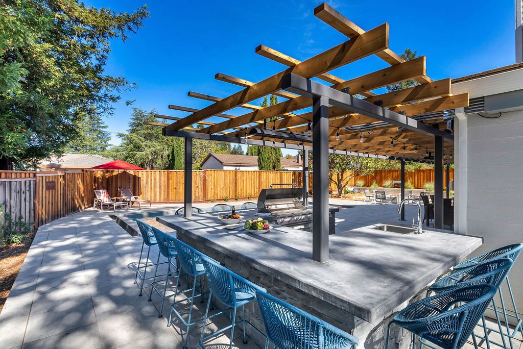 Eine Terrass mit Pergola, Bar und Sitzgelegenheiten.