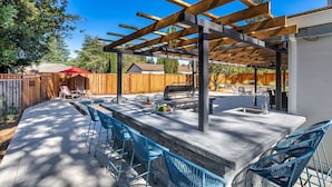 An outdoor patio with a pergola, bar area, and seating.