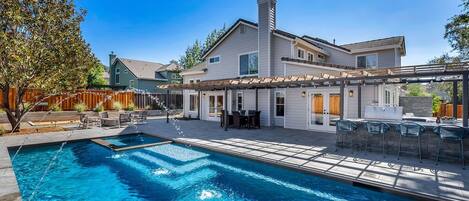 A modern house with a swimming pool, outdoor seating, and a covered patio area.