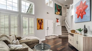 A spacious living area with a large window, a staircase, and a modern art piece on the wall.