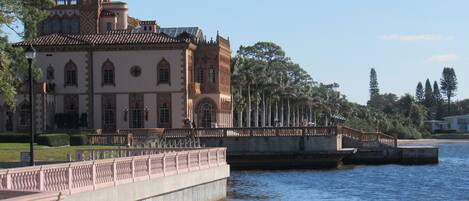 A large, historic building with a tower and multiple windows, situated next to a body of water.