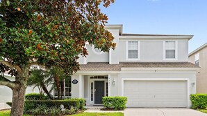 A two-story house with a garage, a front door, and a well-maintained lawn. - 6 bed South Facing Pool/Spa Home Free Heat, Disney (Kissimmee)