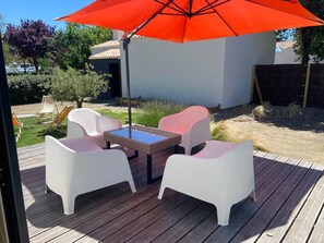 An outdoor patio with a wooden deck, white plastic chairs, a small table, and a red umbrella. - La Maison, ★ L'her beau d'hier 3-bedroom house (sleeps 8) 300m from the beach ★ (L'Épine)