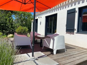 An outdoor patio with a table and chairs, a wooden deck, and a large orange umbrella. - La Maison, ★ L'her beau d'hier 3-bedroom house (sleeps 8) 300m from the beach ★ (L'Épine)