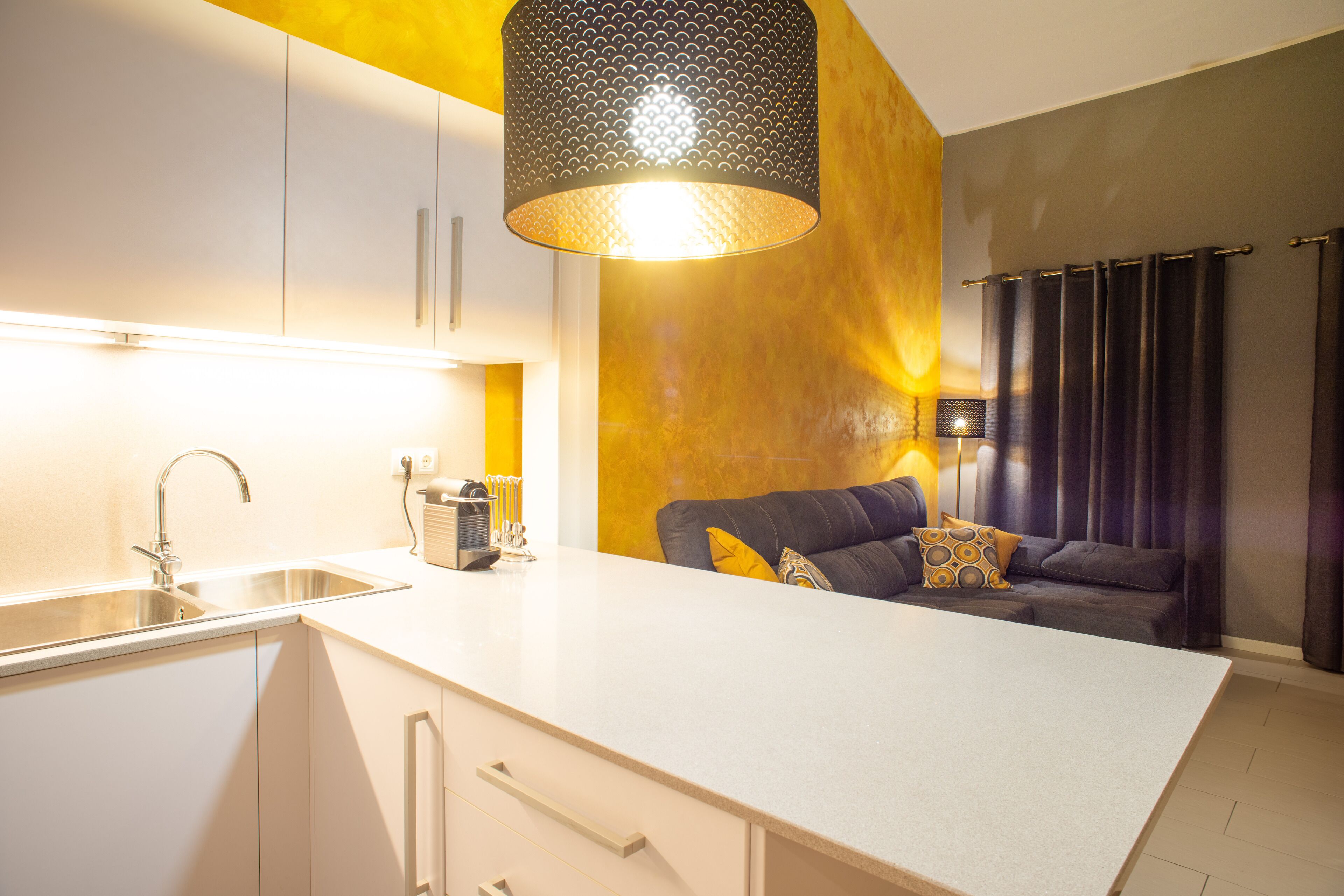 A modern kitchen with a white countertop, a built-in sink, and a pendant light.