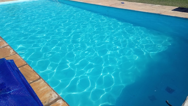 A clear blue swimming pool with a view of the surrounding landscape. - Country house for rent (São Roque)