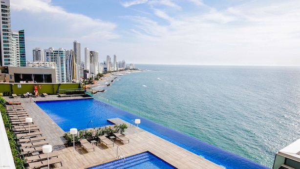 Una piscina en la azotea con vistas al océano y edificios altos.