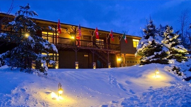 A lodge with a wooden exterior, multiple balconies, and flags. - 5 Free Daily Bryce Resort Passes!  Skiing, Tubing, Golf, Mountain Biking, Lake!  (Basye)