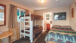 A bunk bed room with a desk, a small cabinet, and a painting on the wall.