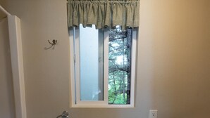 A bathroom with a window, a sink, a mirror, and a towel rack.