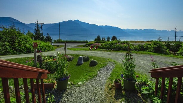 Un jardin avec un chemin de gravier, des plantes en pot et un banc en bois.