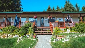 Un chalet doté d’un porche à l’avant, d’un escalier menant à l’entrée et de plusieurs drapeaux.
