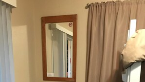 A compact room with a round wooden table and two foldable chairs. A mirror hangs on the wall, and a curtain covers a window. - Cabin 1 Lynn View Lodge (Haines)
