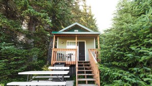 A wooden cabin with a balcony, a grill, and a picnic table. - Cabin 1 Lynn View Lodge (Haines)