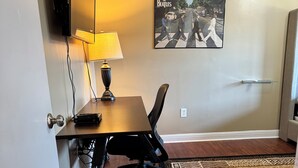 A room with a wooden desk, a black office chair, a lamp, a poster on the wall, and a patterned rug. - NC Music Factory Ranch Getaway (Charlotte)
