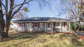 A single-story house with a front porch, a garage, and a large tree in the yard. - NC Music Factory Ranch Getaway (Charlotte)