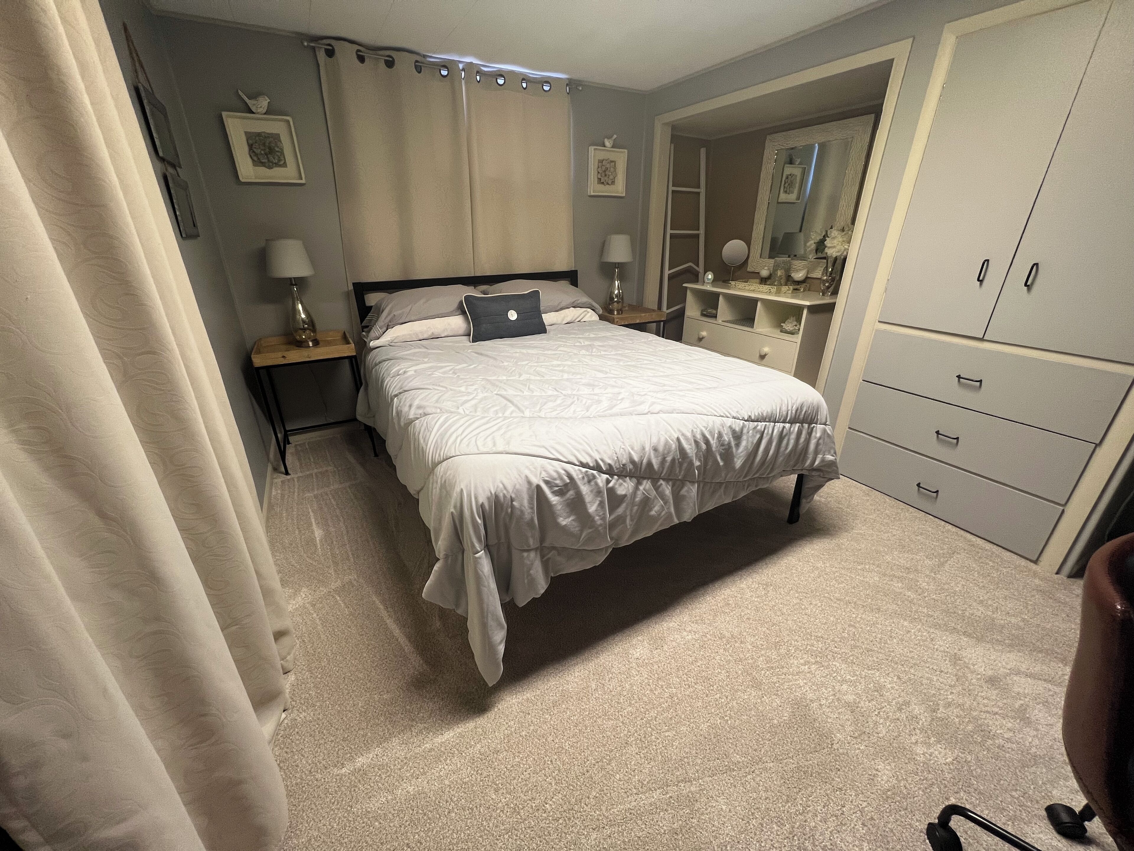 A bedroom with a bed, nightstands, a dresser, and a mirror.