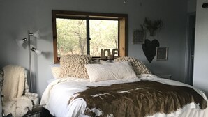 A bedroom with a bed, a window, a ceiling fan, and a chair. - Interior Designer Farm-Style Accommodations in the Pines (Prescott)