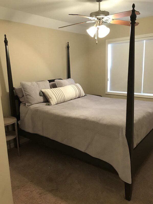 A four-poster bed with a ceiling fan, a window with blinds, and a small bedside table. - Pretty little Cottage (Oxford)