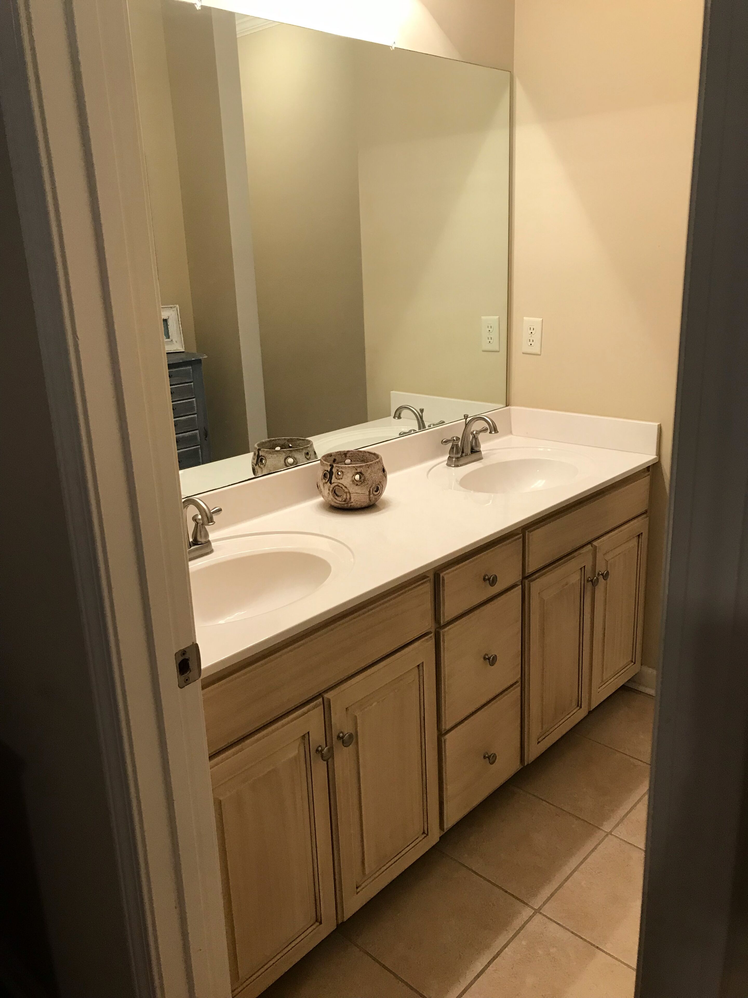 Une salle de bain avec deux lavabos, un grand miroir et des meubles en bois.