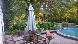 A wooden deck with a pool table, chairs, and an umbrella. - Large 3/4 bedroom Valley View House with Outdoor Space, Pool and Storm Shelter (Jonesboro)