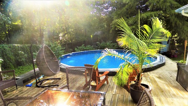 A wooden deck with a pool, wicker furniture, and a palm tree. - Large 3/4 bedroom Valley View House with Outdoor Space, Pool and Storm Shelter (Jonesboro)