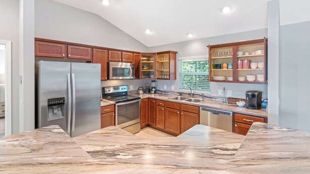 A modern kitchen with stainless steel appliances, wooden cabinets, and a marble countertop. - Ruhe Haus in Collier. 3/2, FREE golf, 4-seat cart, RESIDENT passes, pets (The Villages)