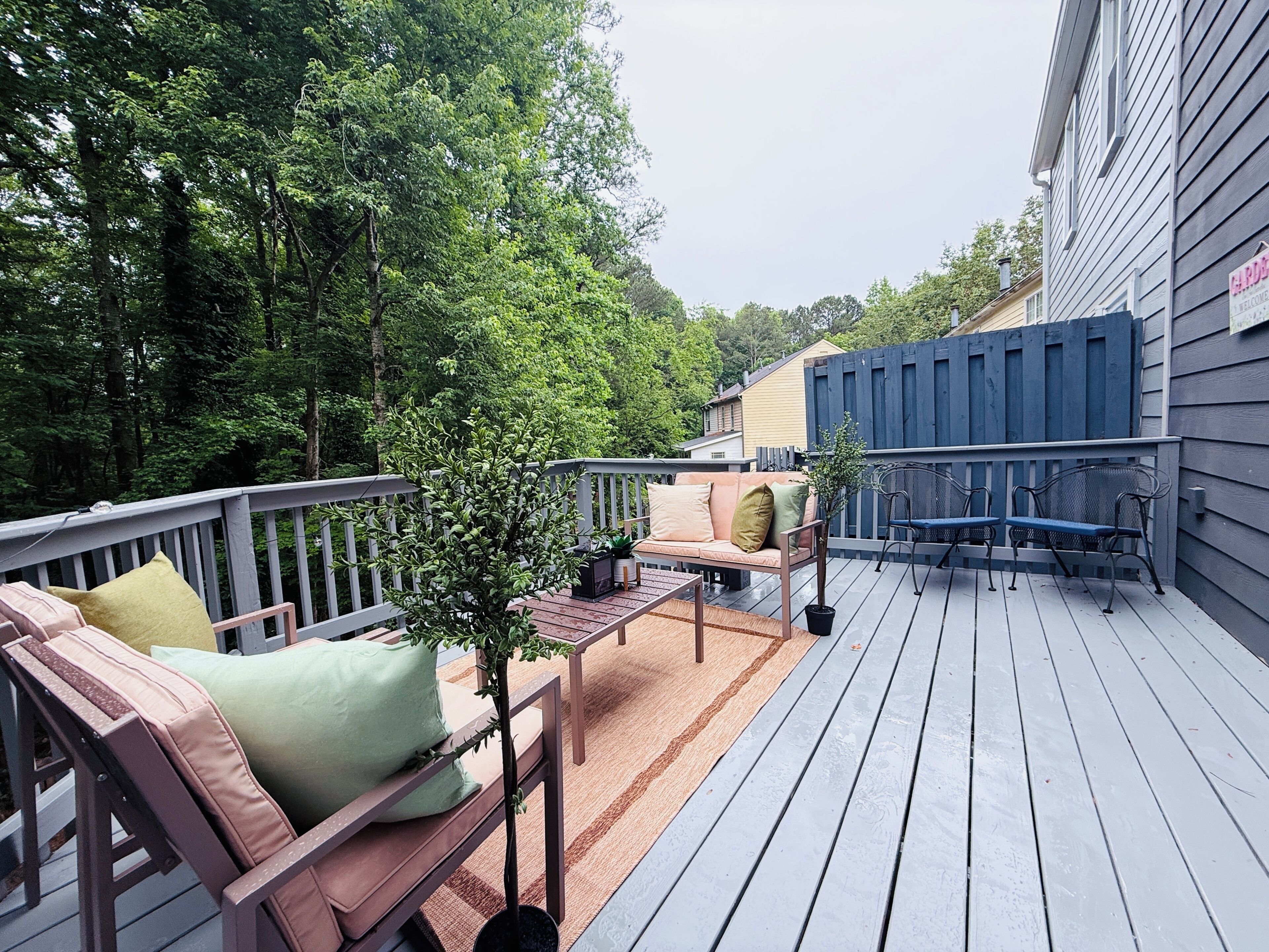 A deck with a sofa and chairs, surrounded by trees.