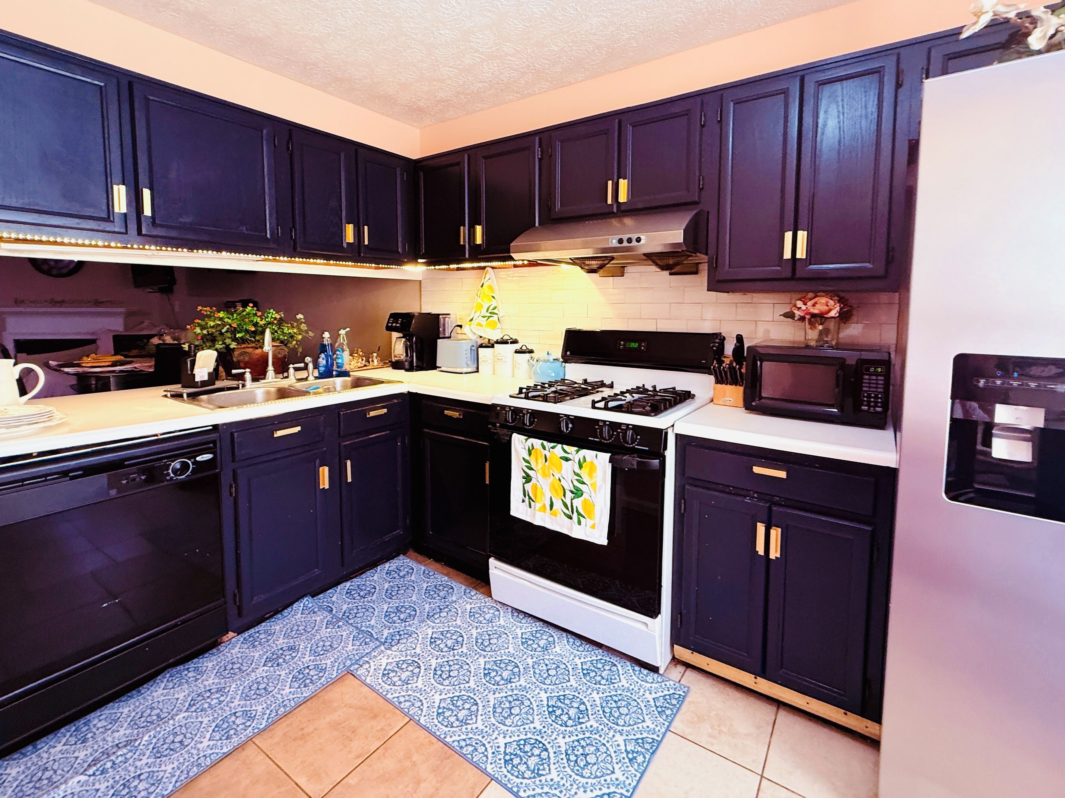 A kitchen with dark cabinets, a stove, microwave, and a dishwasher.