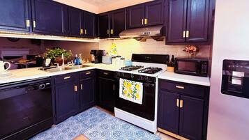A kitchen with dark cabinets, a stove, microwave, and a dishwasher.