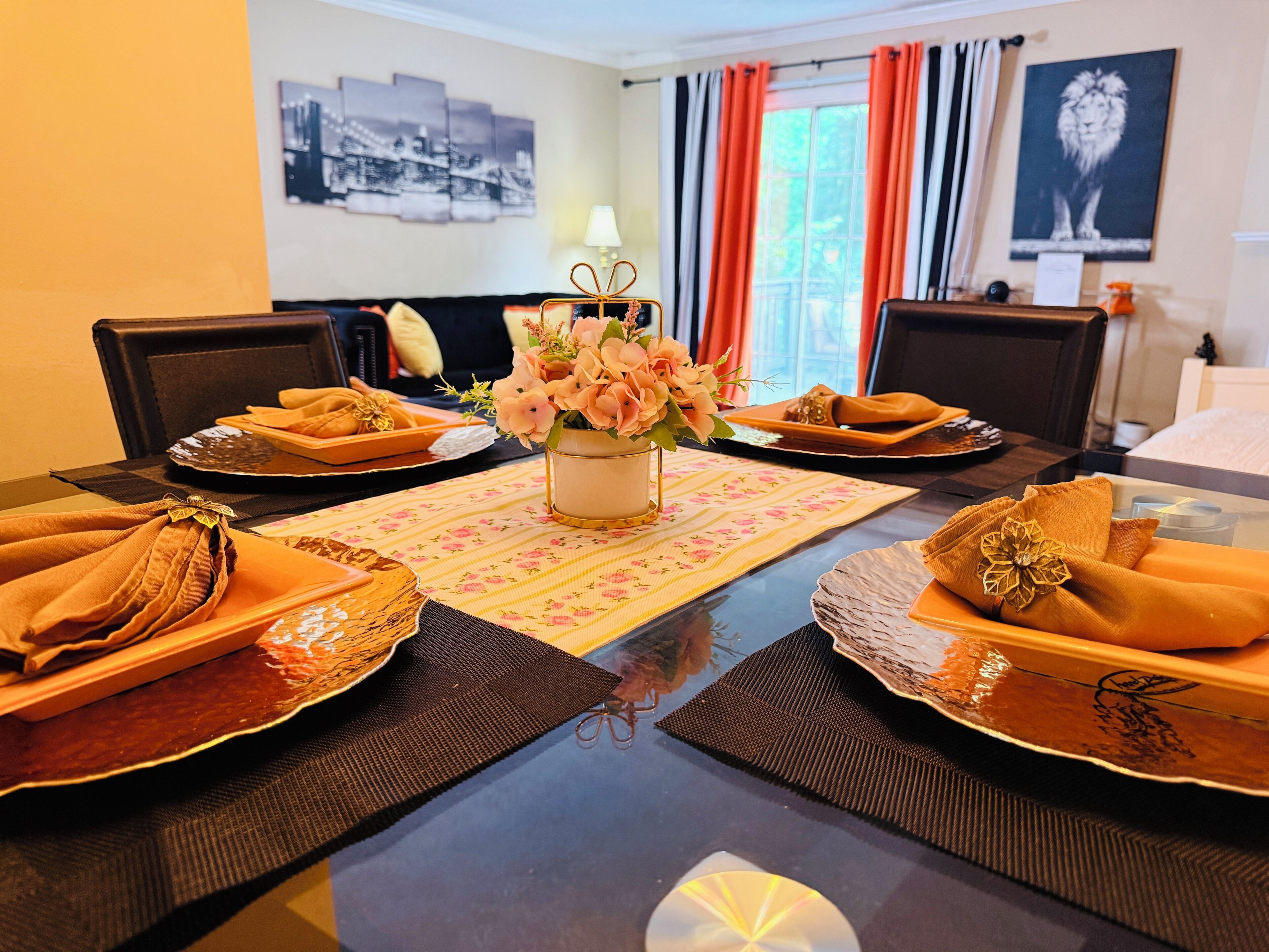 A dining table set with folded napkins, a vase with flowers, and a placemat.
