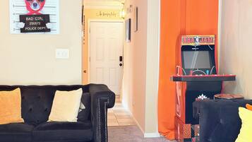 A living room with a black sofa, a small table, and an orange curtain.