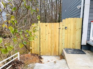 A wooden gate with a small mailbox, a white fence, and a concrete step leading to a house. - Sweet Home Georgia (Norcross)