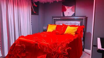 Camera da letto con copriletto rosso, testiera grigia e un'opera d'arte incorniciata sopra il letto.