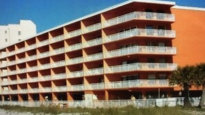 A multi-story hotel with a red facade and balconies. - Chateaux #406  Charming Beachfront Retreat with spectacular views! (Indian Shores)